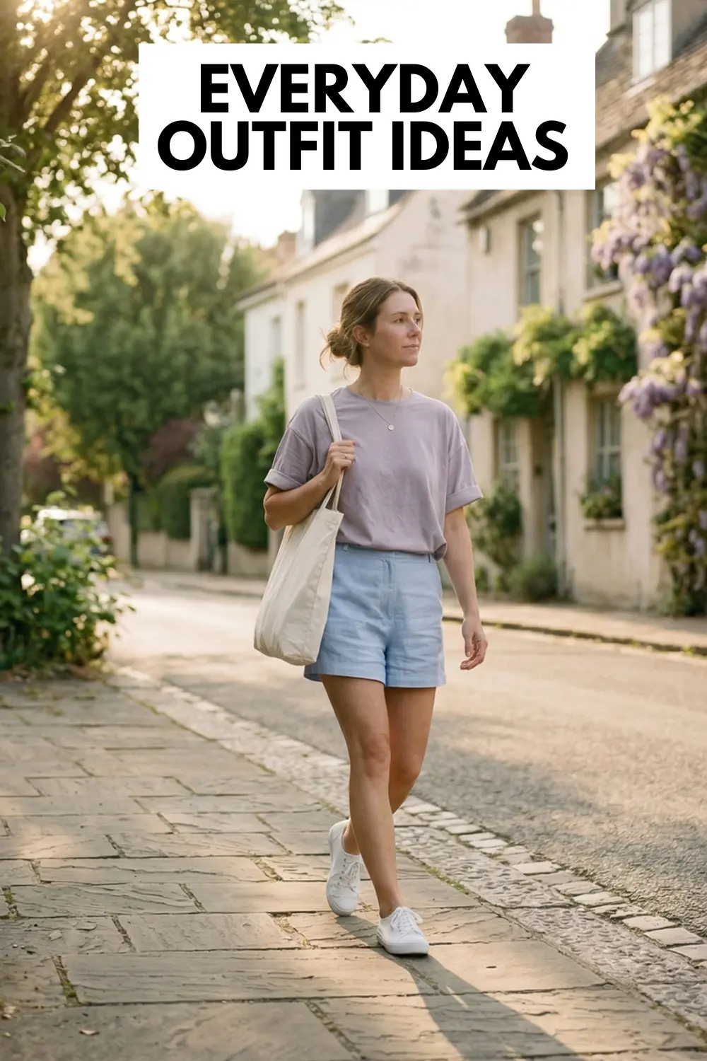Woman walking on a quiet street wearing women's shorts, oversized t-shirt, sneakers and carrying a tote bag in soft sunlight